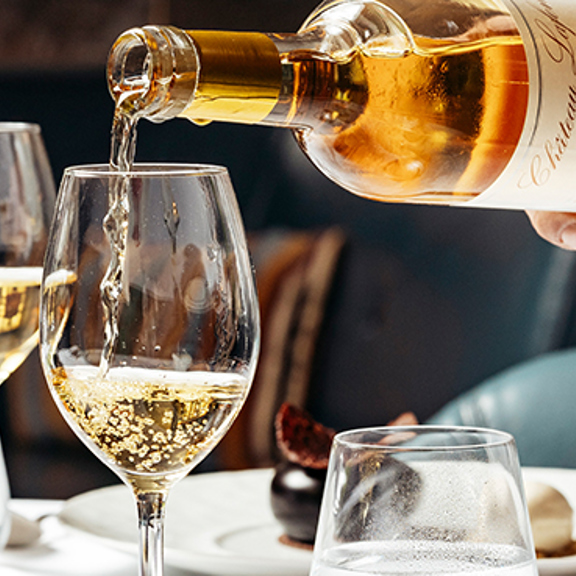 Wine being poured into two wine glasses on a table